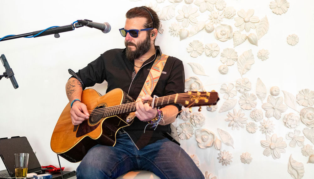 Man in sunglasses playing acoustic guitar at Aveline